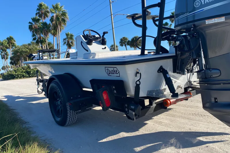 Slide: The Image of 2024 Drake Boatworks Nomad on trailer, parked on sunny road with palm trees. - 5