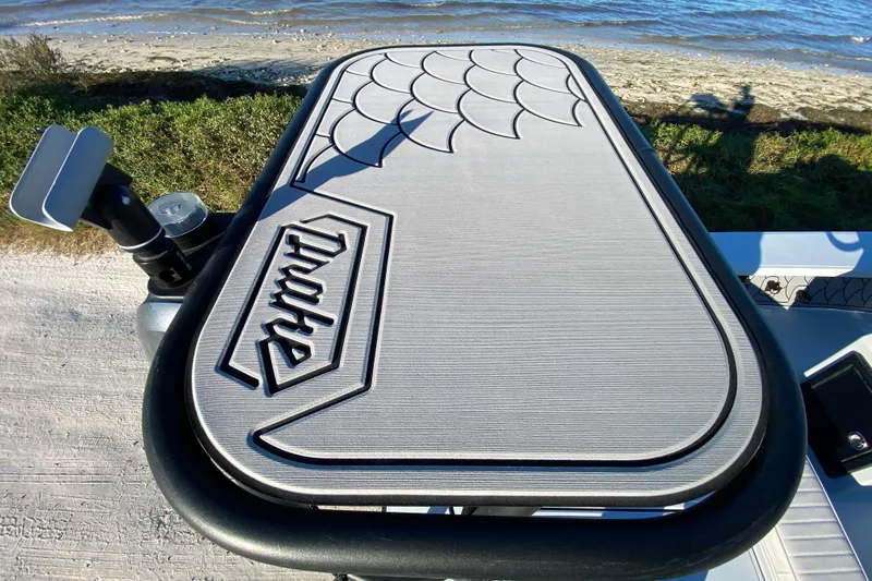 Slide: The Image of 2024 Drake Boatworks Nomad deck with logo, near shoreline and water. - 67