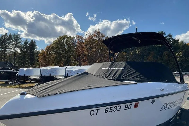 Slide: The Image of 2015 Moomba Outback V boat with cover, parked outdoors under a partly cloudy sky. - 10