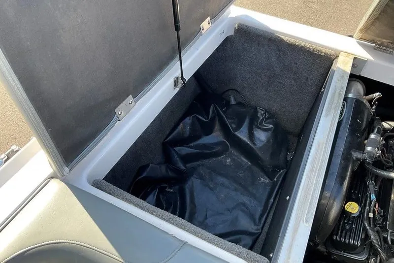 Slide: The Image of Open storage compartment in 2015 Moomba Outback V boat, showing engine and black cover. - 17