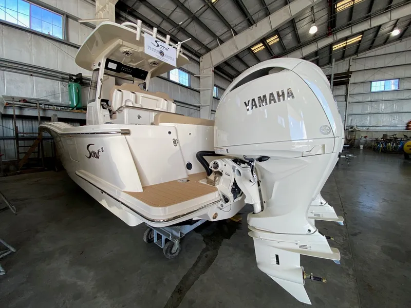 Slide: The Image of 2026 Scout 260 LXF boat displayed outdoors on gravel lot under clear blue sky. - 2