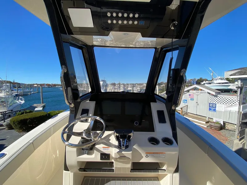 Slide: The Image of 2026 Scout 260 LXF boat helm with steering wheel and control panel, docked at marina. - 6