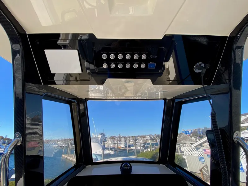 Slide: The Image of Interior view of 2026 Scout 260 LXF boat, showcasing control panel and marina backdrop. - 8
