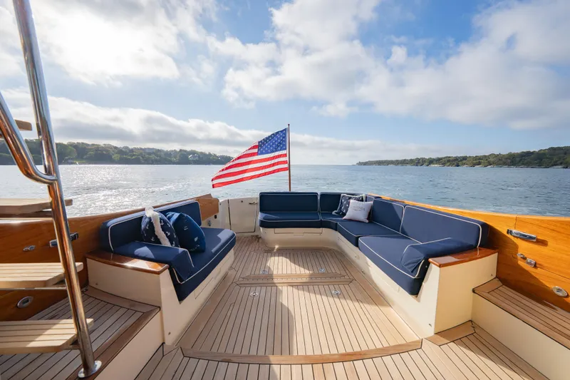 Slide: The Image of 2013 Hinckley Talaria 48 Flybridge yacht with elegant seating and American flag on open water. - 12