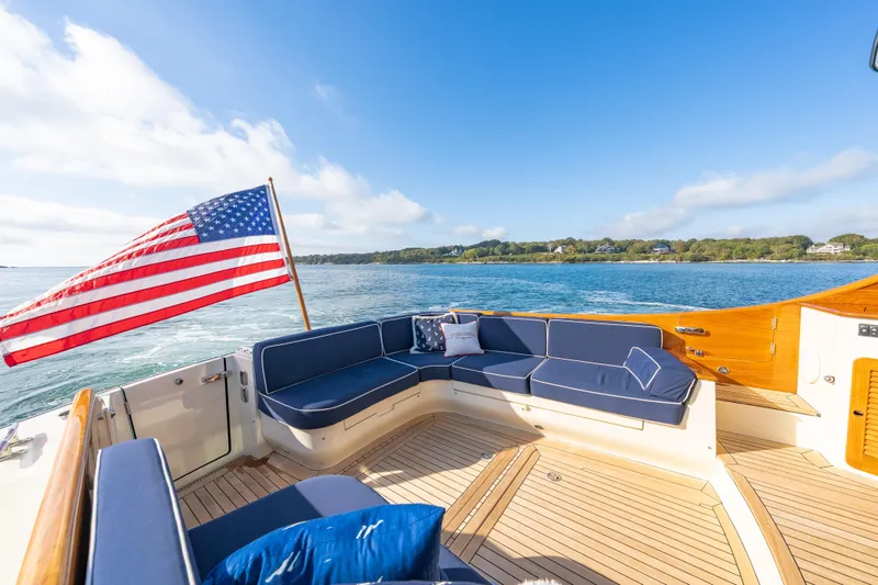 Slide: The Image of Hinckley Talaria 48 Flybridge 2013 yacht with American flag, blue seating, and scenic ocean view. - 13
