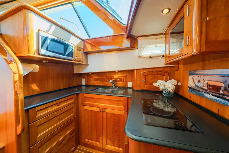 Slide: The Image of Luxurious 2013 Hinckley Talaria 48 Flybridge yacht kitchen with wood cabinetry and modern appliances. - 26