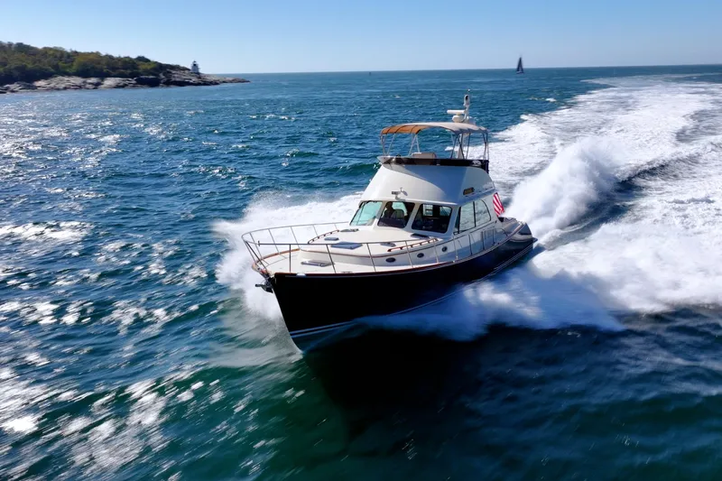 Slide: The Image of 2013 Hinckley Talaria 48 Flybridge cruising on open sea near rocky coastline. - 36