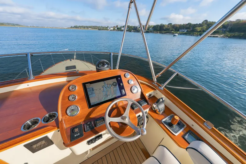 Slide: The Image of Helm of 2013 Hinckley Talaria 48 Flybridge with navigation display, overlooking serene waters. - 4