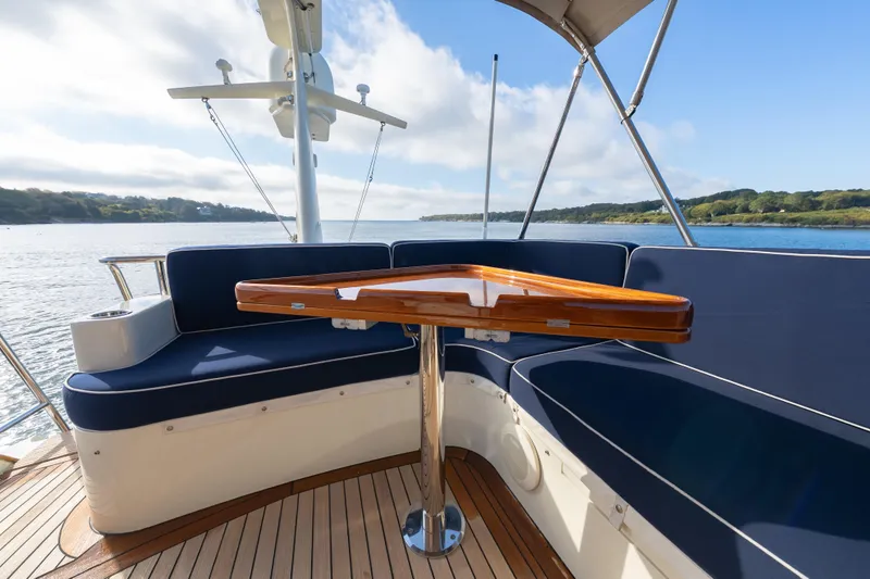 Slide: The Image of 2013 Hinckley Talaria 48 Flybridge with elegant seating and wooden table on deck. - 9