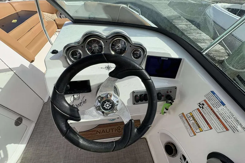 Slide: The Image of 2024 NauticStar 223 DC boat dashboard with steering wheel and control panel. - 13