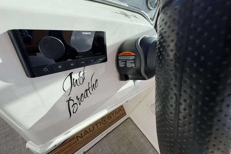 Slide: The Image of 2024 NauticStar 223 DC dashboard with Fusion audio system and "Just Breathe" text. - 14