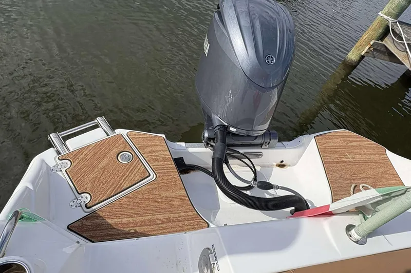Slide: The Image of 2024 NauticStar 223 DC boat with Yamaha outboard motor, docked on calm water. - 16