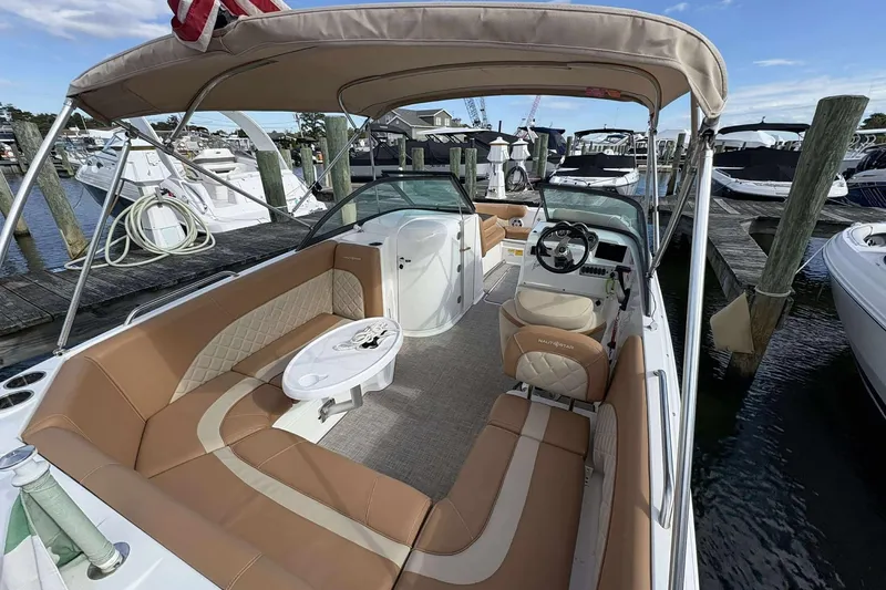 Slide: The Image of 2024 NauticStar 223 DC boat interior with tan seating and helm, docked at marina. - 17