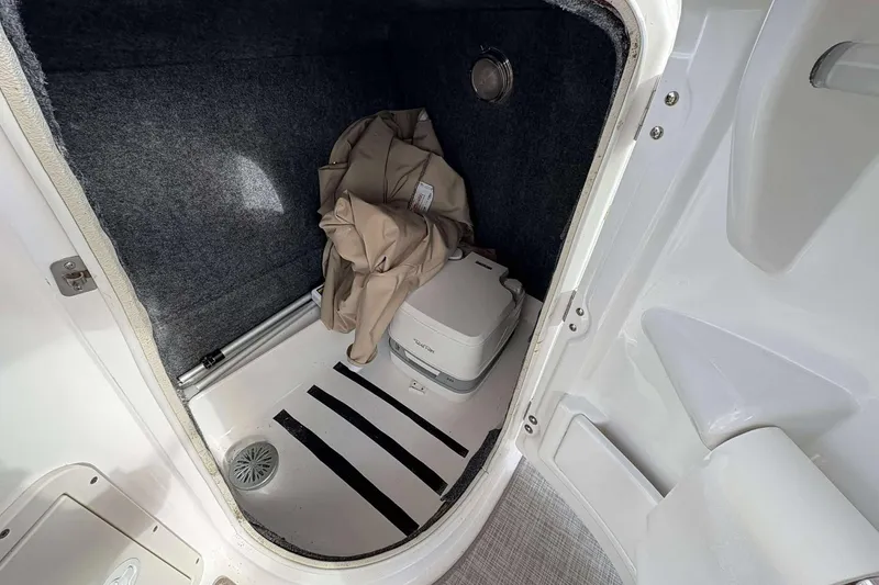 Slide: The Image of 2024 NauticStar 223 DC boat interior with storage compartment and portable toilet. - 24