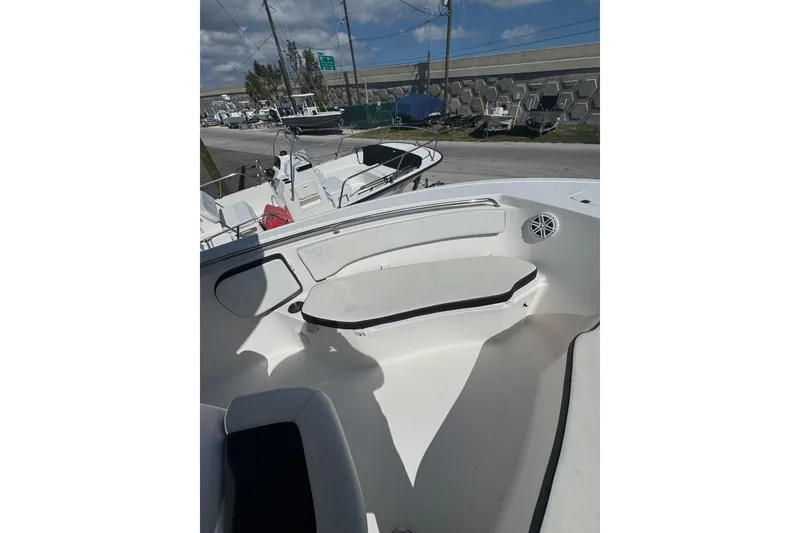 Slide: The Image of 2021 Tidewater 220 LXF boat interior with seating and speaker, parked outdoors. - 10