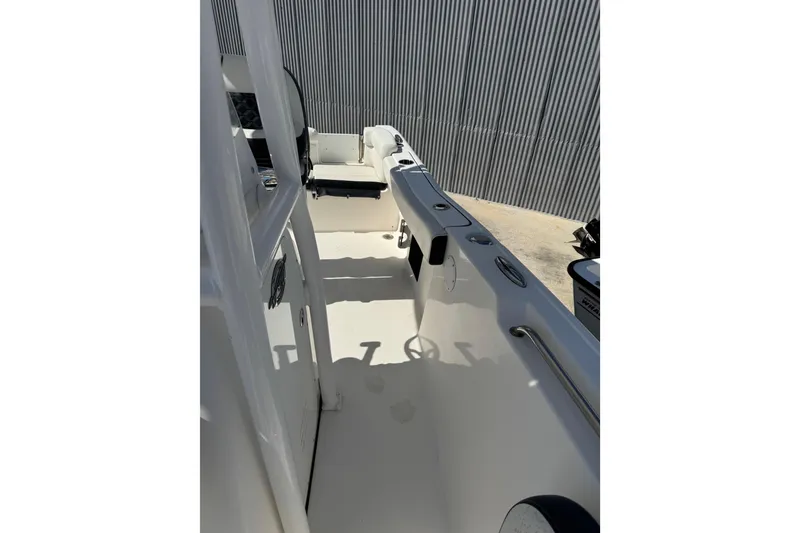 Slide: The Image of 2021 Tidewater 220 LXF boat interior with seating and railing, parked outdoors. - 13