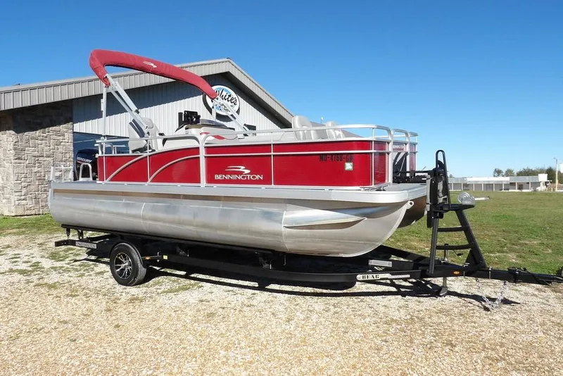 The Image of 2022 Bennington 20 SVF pontoon boat on trailer, red and silver design, parked outdoors. - 1