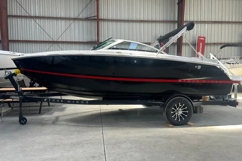 Slide: The Image of 2026 Four Winns H1 Freedom boat in a warehouse, black with red accents. - 11