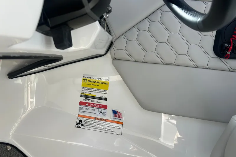 Slide: The Image of 2026 Four Winns H1 Freedom boat interior with capacity warning label, seating, and steering wheel. - 17
