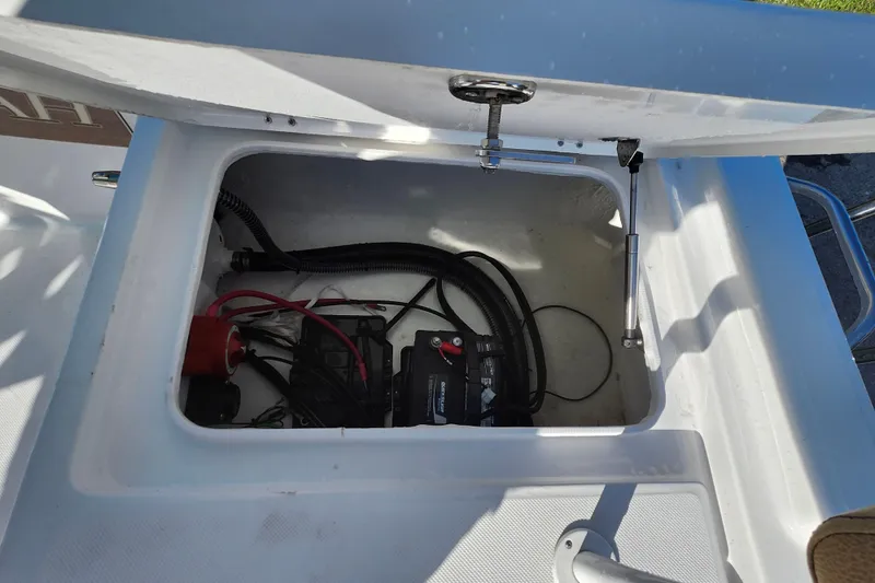 Slide: The Image of Open storage compartment in 2026 Savannah 220 IS boat, showing battery and wiring. - 34