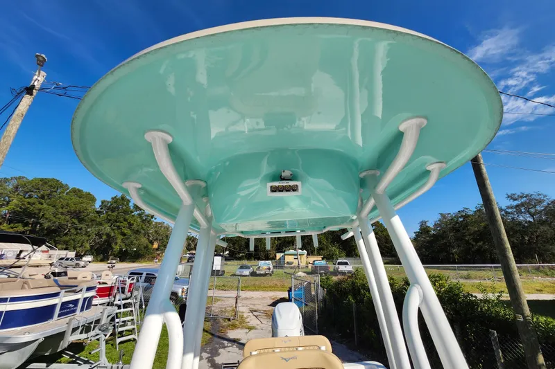 Slide: The Image of 2026 Savannah 220 IS boat with teal canopy, parked outdoors under clear blue sky. - 38