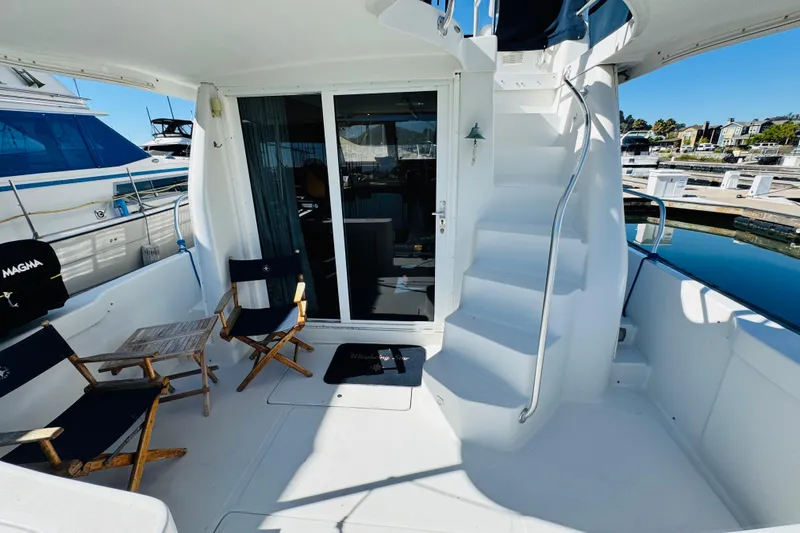 Slide: The Image of 2000 Mainship 390 Trawler deck with chairs, table, and stairs in a marina setting. - 13