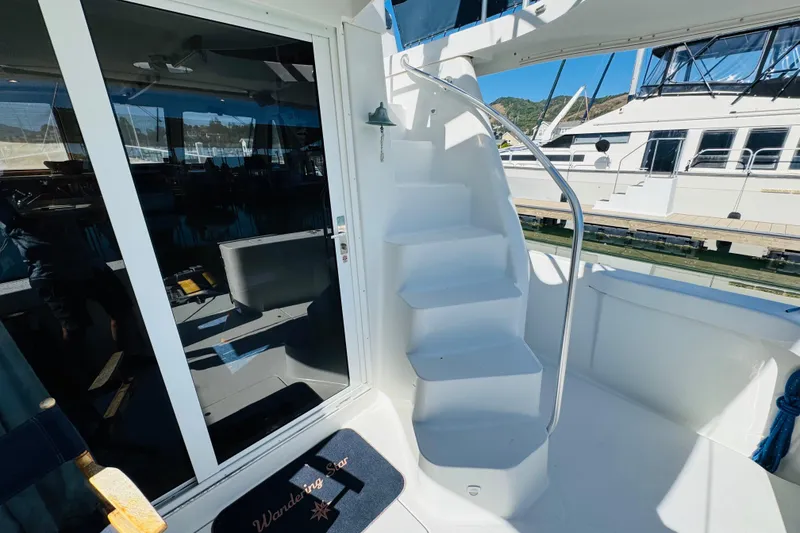 Slide: The Image of 2000 Mainship 390 Trawler with white stairs and glass door, docked at marina. - 15