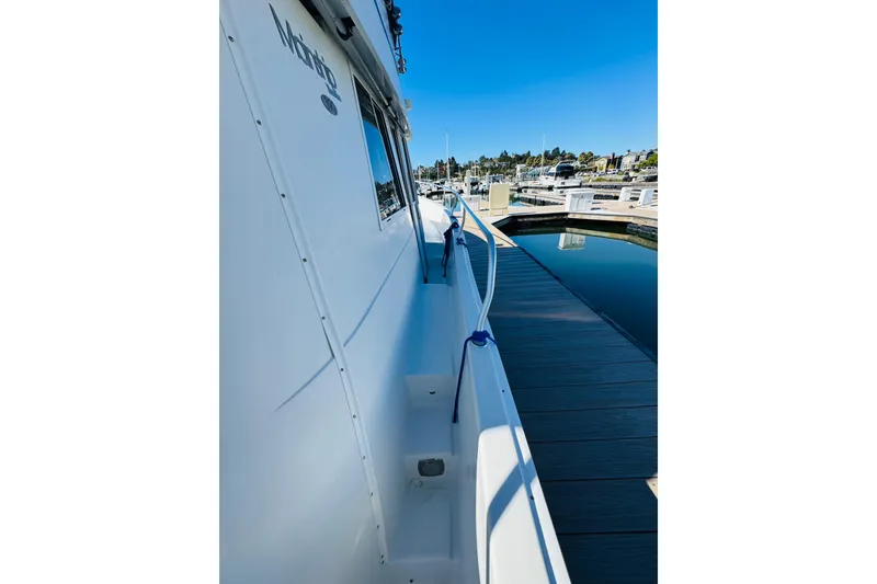 Slide: The Image of 2000 Mainship 390 Trawler docked at marina, side view with clear blue sky. - 16