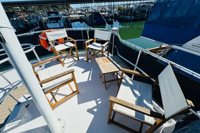 Slide: The Image of Deck of 2000 Mainship 390 Trawler with chairs and table, docked at marina. - 26