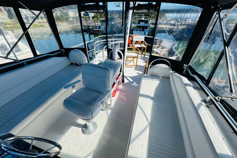Slide: The Image of 2000 Mainship 390 Trawler interior with white seating and helm, docked at marina. - 37