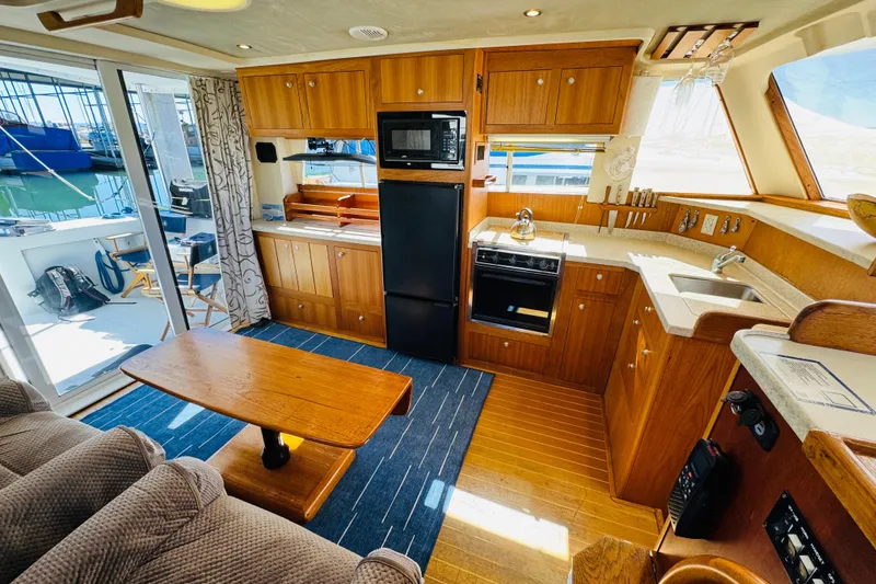 Slide: The Image of 2000 Mainship 390 Trawler interior with wooden cabinetry, kitchenette, and seating area. - 46