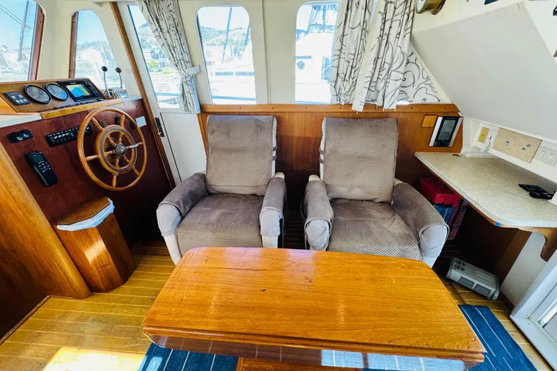Slide: The Image of 2000 Mainship 390 Trawler interior with helm, plush chairs, and wooden table. - 48
