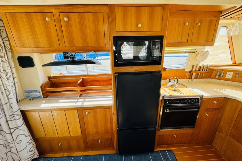Slide: The Image of 2000 Mainship 390 Trawler kitchen with wooden cabinets, stove, and microwave. - 49