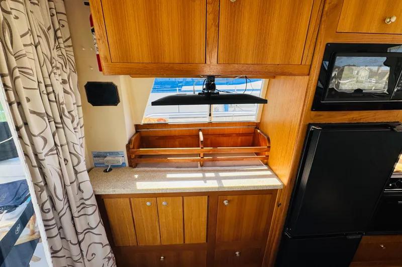Slide: The Image of 2000 Mainship 390 Trawler interior with wooden cabinets and countertop, featuring a window view. - 50