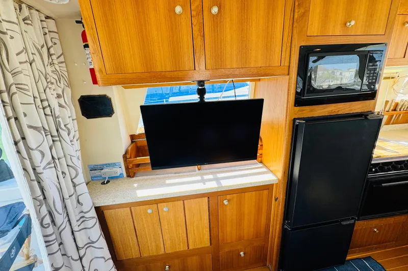 Slide: The Image of 2000 Mainship 390 Trawler interior with wood cabinetry, TV, microwave, and refrigerator. - 51