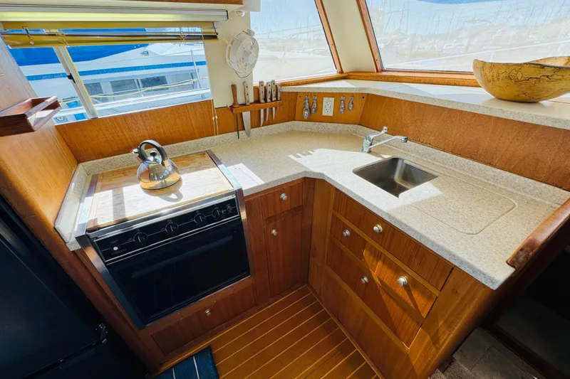 Slide: The Image of Cozy kitchen in 2000 Mainship 390 Trawler with stove, sink, and wooden cabinetry. - 52