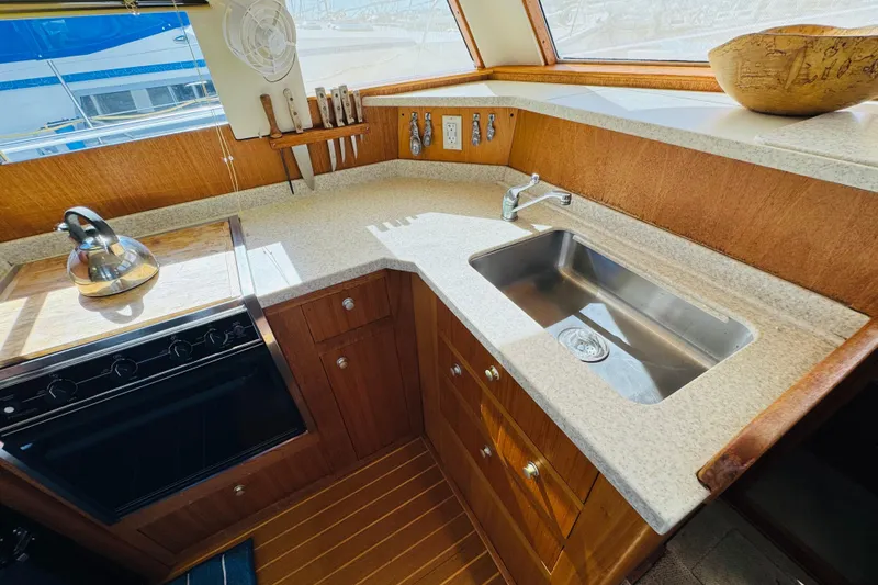 Slide: The Image of Mainship 390 Trawler 2000 kitchen with sink, stove, and wooden cabinetry. - 53