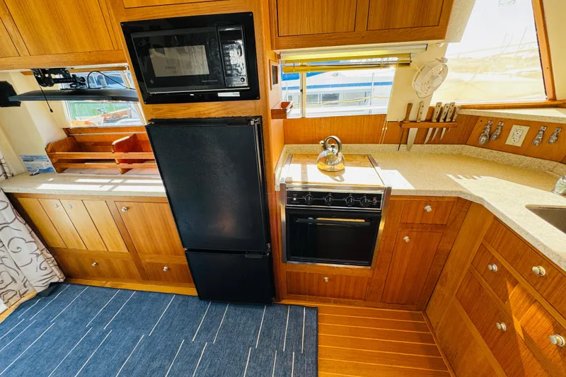 Slide: The Image of Kitchen area of 2000 Mainship 390 Trawler with wooden cabinets and modern appliances. - 54