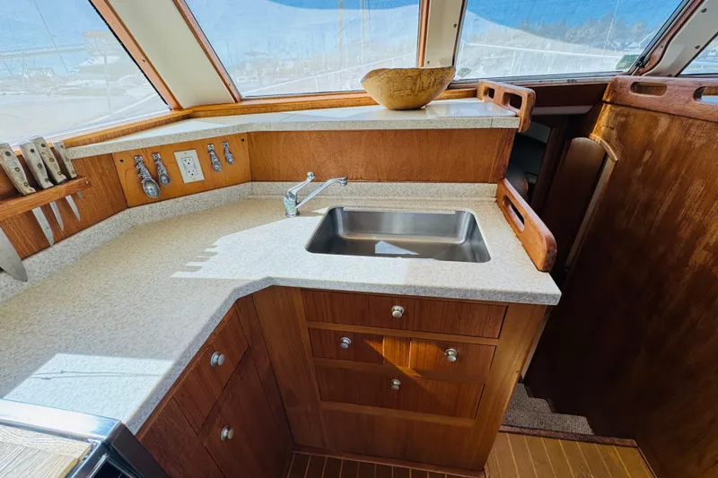 Slide: The Image of 2000 Mainship 390 Trawler kitchen with sink, wooden cabinetry, and countertop. - 56
