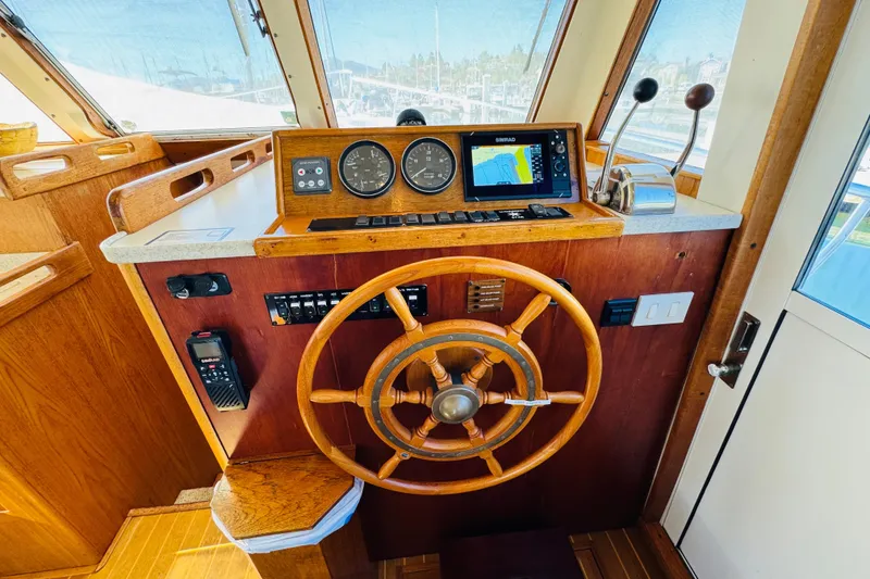 Slide: The Image of 2000 Mainship 390 Trawler helm with wooden wheel, navigation instruments, and controls. - 57