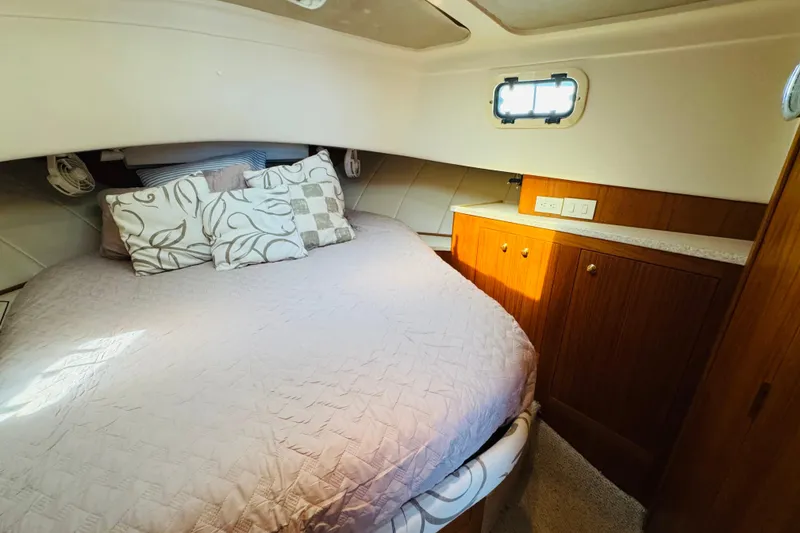 Slide: The Image of Cozy bedroom in 2000 Mainship 390 Trawler with plush bedding and wooden cabinetry. - 64