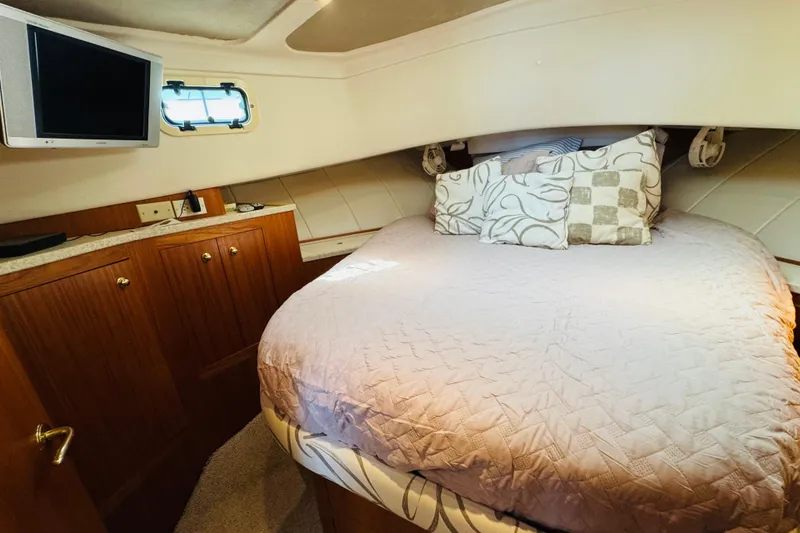 Slide: The Image of Cozy bedroom in 2000 Mainship 390 Trawler with TV, wood cabinets, and plush bedding. - 65