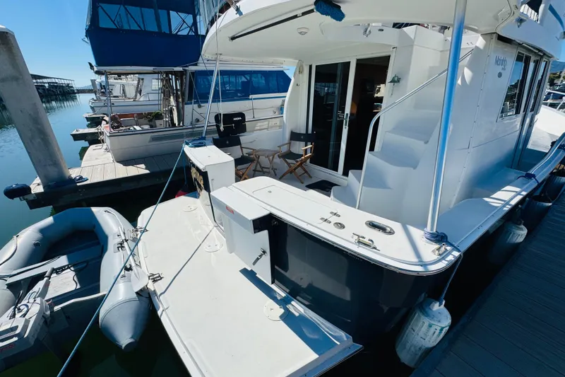 Slide: The Image of 2000 Mainship 390 Trawler docked, featuring spacious deck and inflatable dinghy. - 7