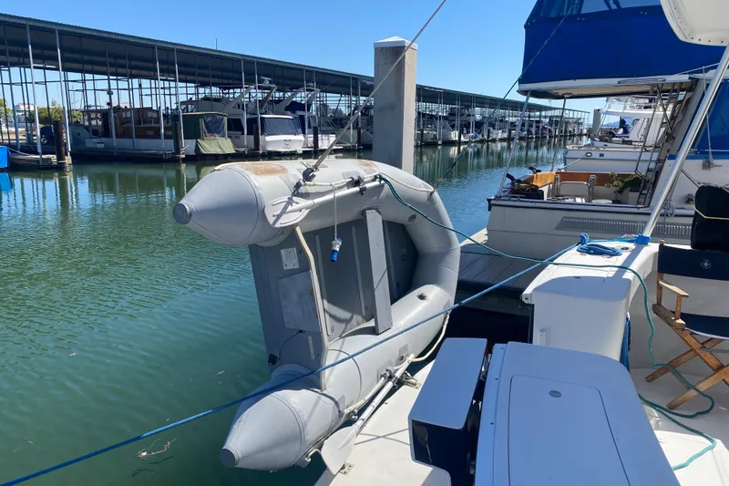 Slide: The Image of 2000 Mainship 390 Trawler docked with inflatable boat, marina background. - 79