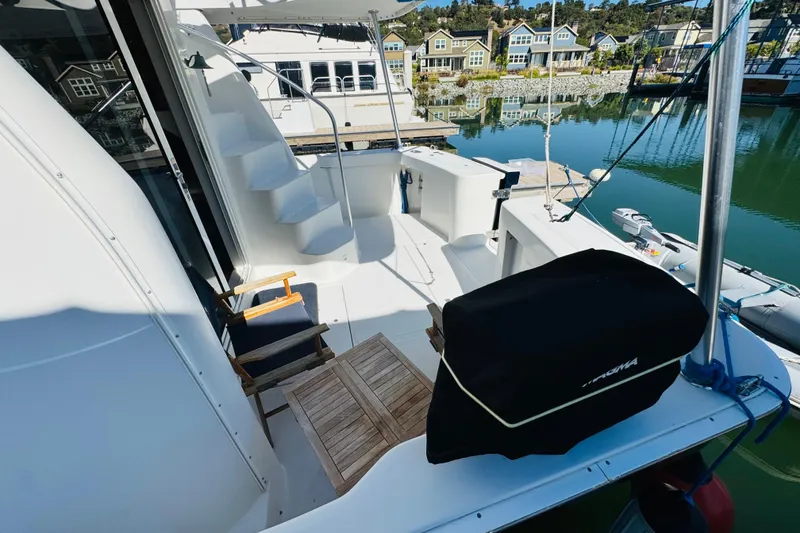 Slide: The Image of 2000 Mainship 390 Trawler deck with seating, table, and marina view. - 9