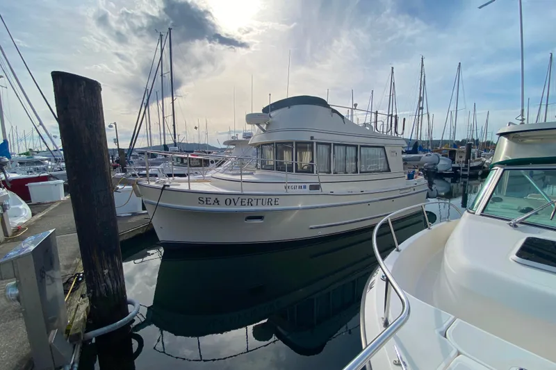 The Image of Camano 30 boat named "Sea Overture" docked at a marina under a cloudy sky. - 0