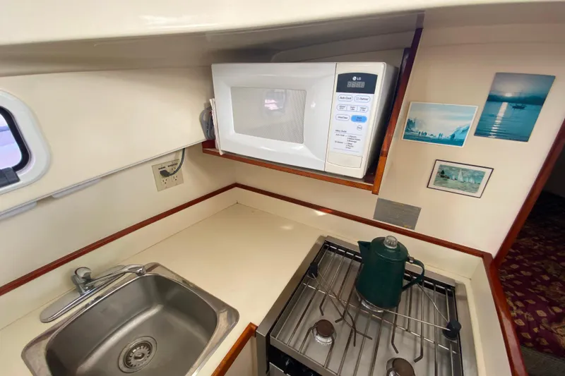 Slide: The Image of Compact galley in Camano 30 boat with microwave, sink, and stove. - 18