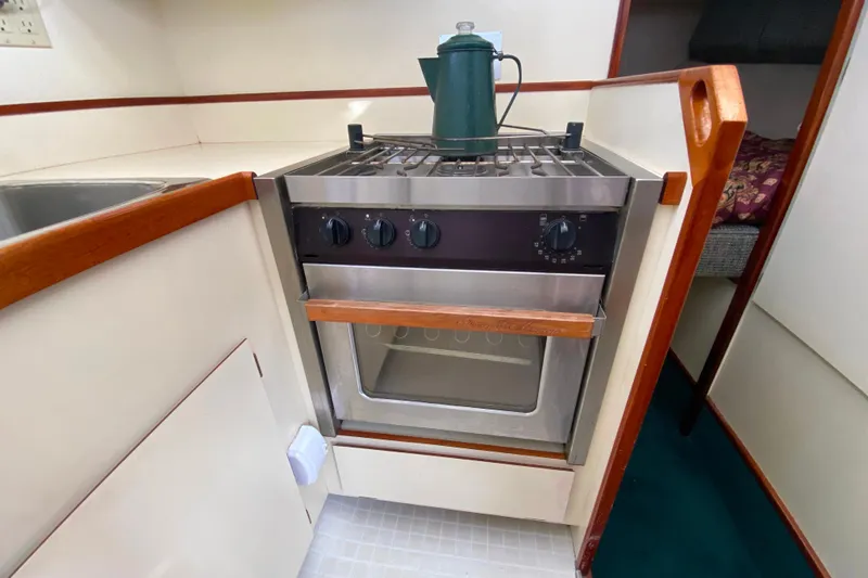Slide: The Image of Camano 30 boat kitchen with stove, oven, and green kettle on countertop. - 19