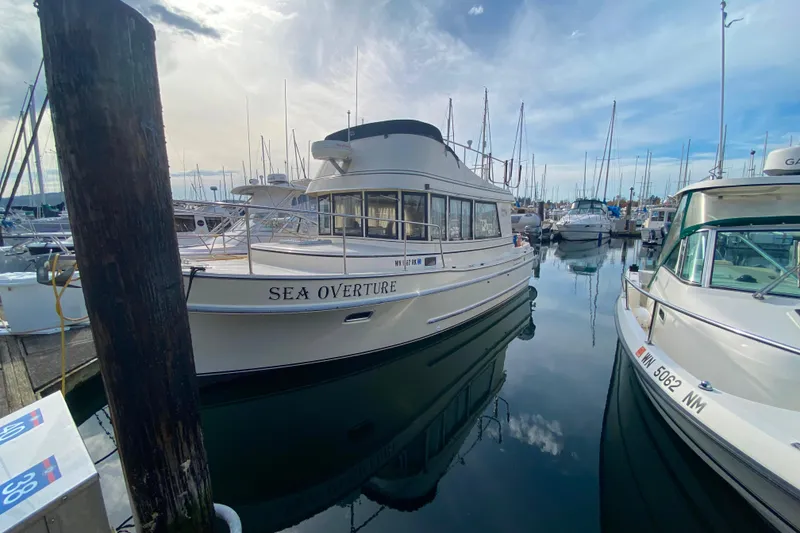 Slide: The Image of Camano 30 boat named "Sea Overture" docked at a marina under a cloudy sky. - 2
