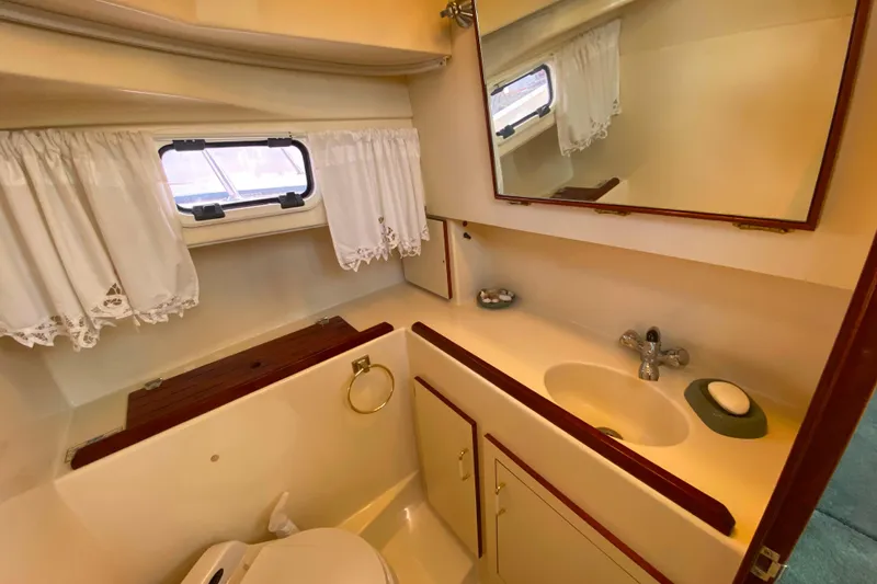Slide: The Image of Camano 30 boat bathroom with sink, mirror, and window with white curtains. - 25